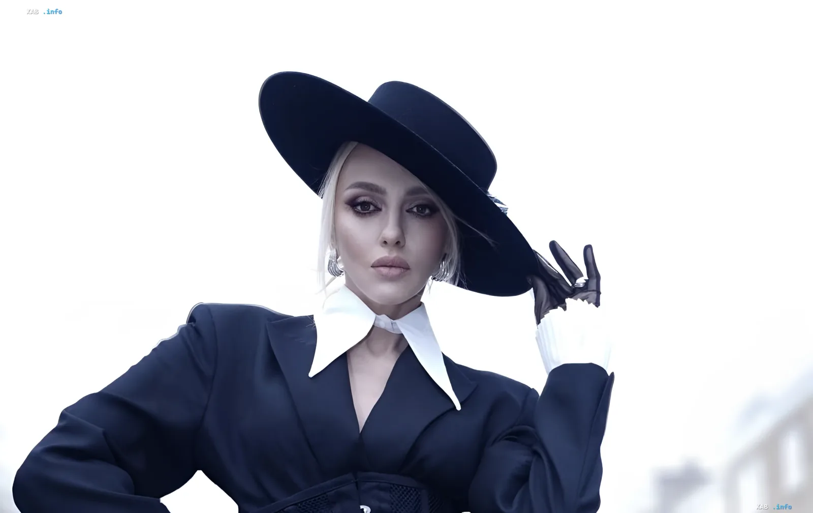Olya Polyakova in a black hat and strict suit amid the loss of her dog Mimi