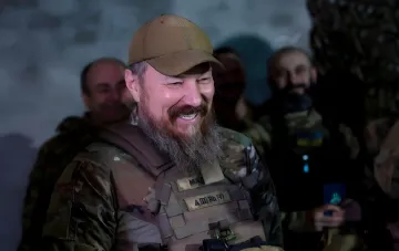 «Мадяр» в камуфляже и тактическом жилете с нашивкой «МАД» на фоне бойцов 427-й бригады СБС «Рарог»