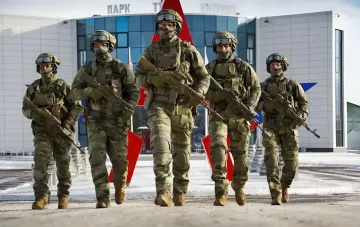 Five camouflaged soldiers with rifles march in formation — illustration for the story on a Russian intelligence network indicted by the US for plotting assassinations