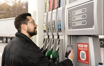 Водитель заправляется на АЗС OKKO и оплачивает топливо по QR-коду, на дисплее автомата отображается цена за литр бензина и дизеля