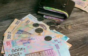 Ukrainische Hrywnja-Scheine und eine Geldbörse vor dem Hintergrund der Nachricht über die Kürzung der Budgetfinanzierung ab dem 15. September