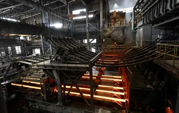 Glowende Stahlstangen auf einem Förderband in einer Metinvest-Stahlhütte, die den kritischen Zustand der ukrainischen Metallurgie veranschaulichen
