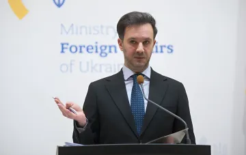 Представитель МИД Украины за трибуной с микрофоном на фоне логотипа министерства иностранных дел во время комментария о местонахождении экс-генпрокурора Кравченко