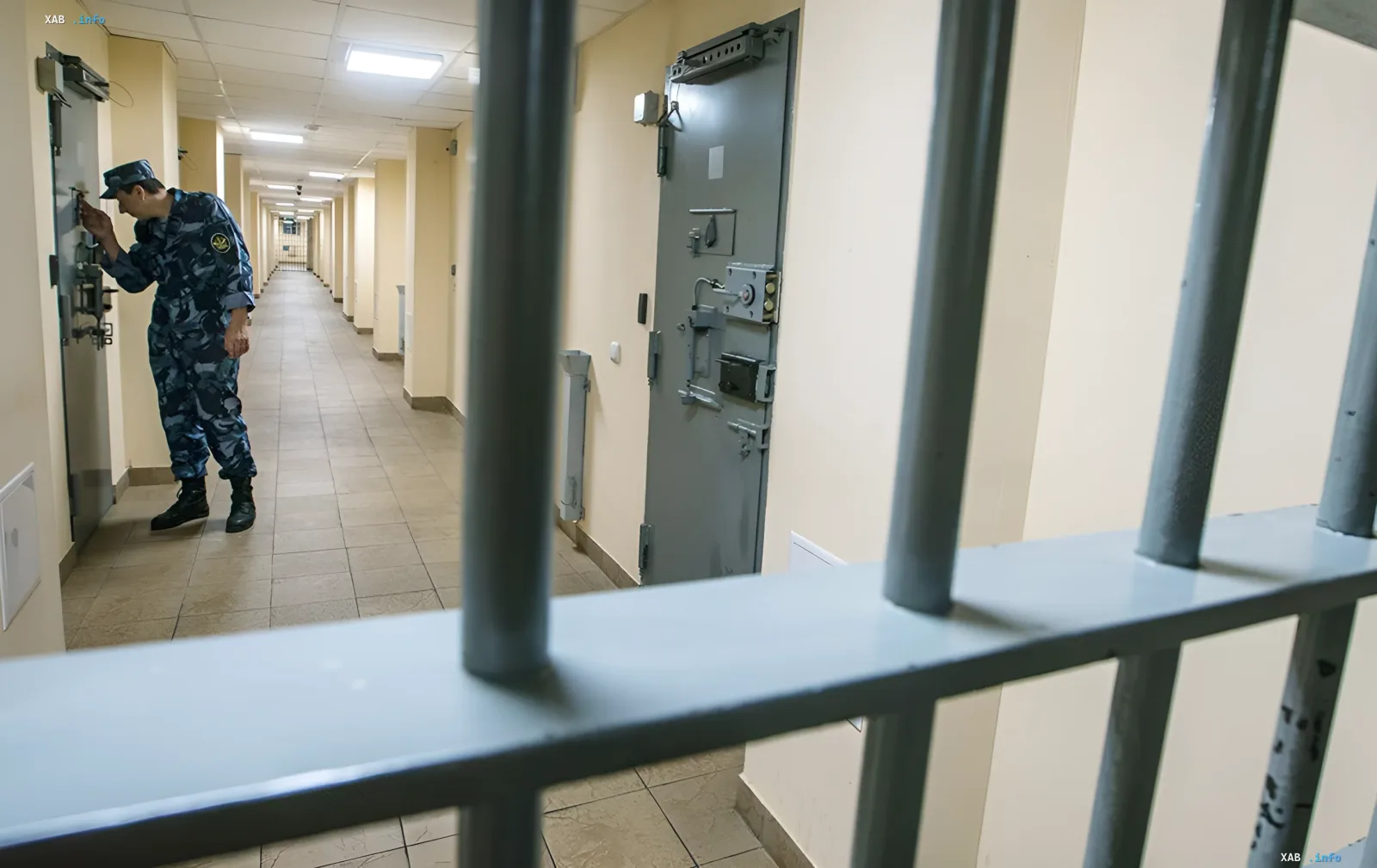 Guard in camouflage checks a heavy cell door in a Russian prison corridor — illustration of new 'super-prison' construction plans