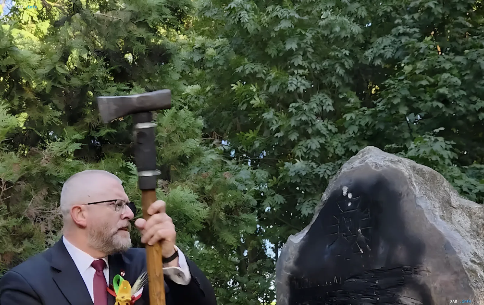 Mann im Anzug mit einer Axt neben einem beschädigten UPA-Denkmal in Polen
