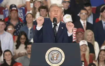 Donald Trump speaking at a podium bearing the Seal of the President of the United States, gesturing emphatically amid his tariff threats toward the EU and Canada