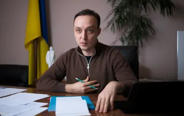 Павло Власюк за рабочим столом в кабинете с украинским флагом на фоне