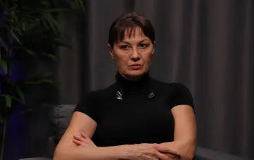 Лариса Руснак в чорній водолазці на тлі темного інтер'єру під час інтерв'ю про останні дні життя своєї матері