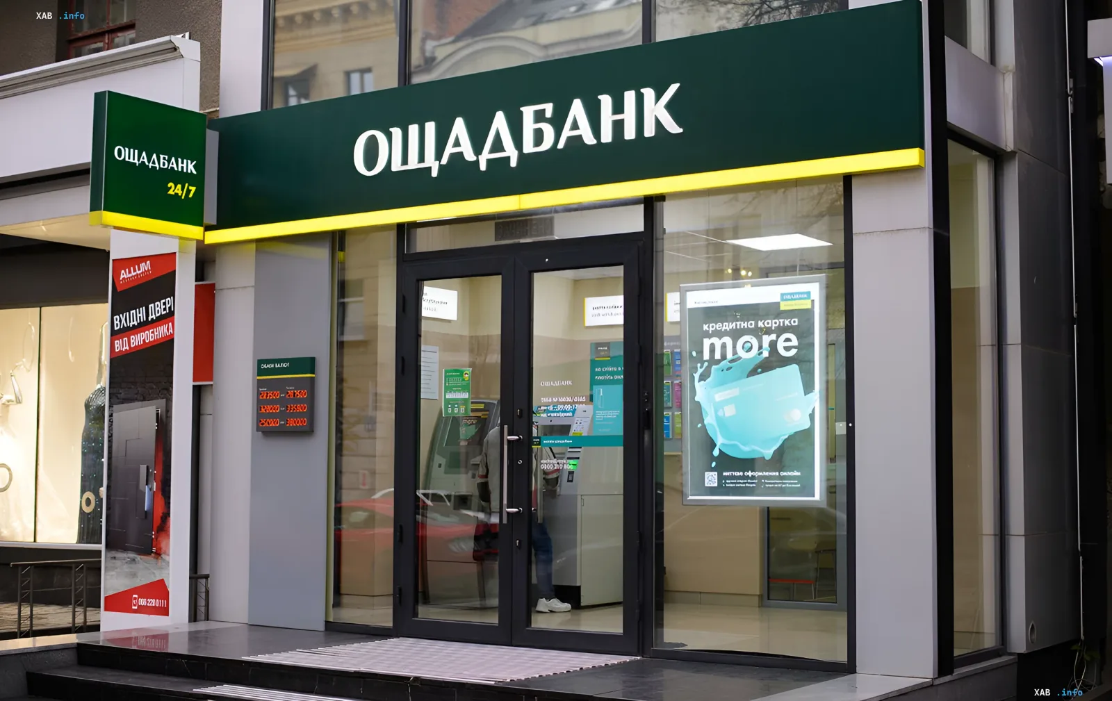 Фасад отделения Ощадбанка с вывеской и витриной на фоне сообщений о сбоях электронных сервисов
