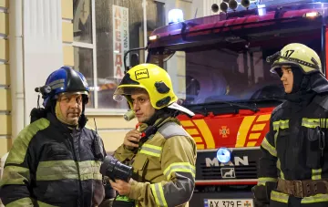 Пожарные у автомобиля на месте возгорания в торговом центре Харькова после удара российского дрона