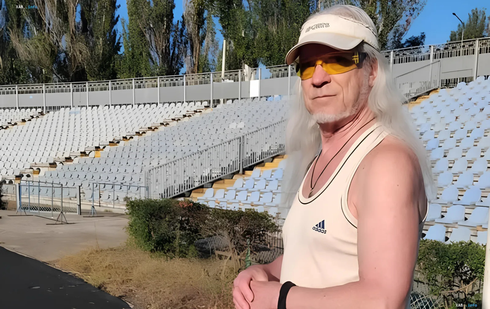 Läufer mit langem silbernem Haar in weißer Kappe und gelber Brille auf den Rängen des Zentralstadions in Mykolajiw