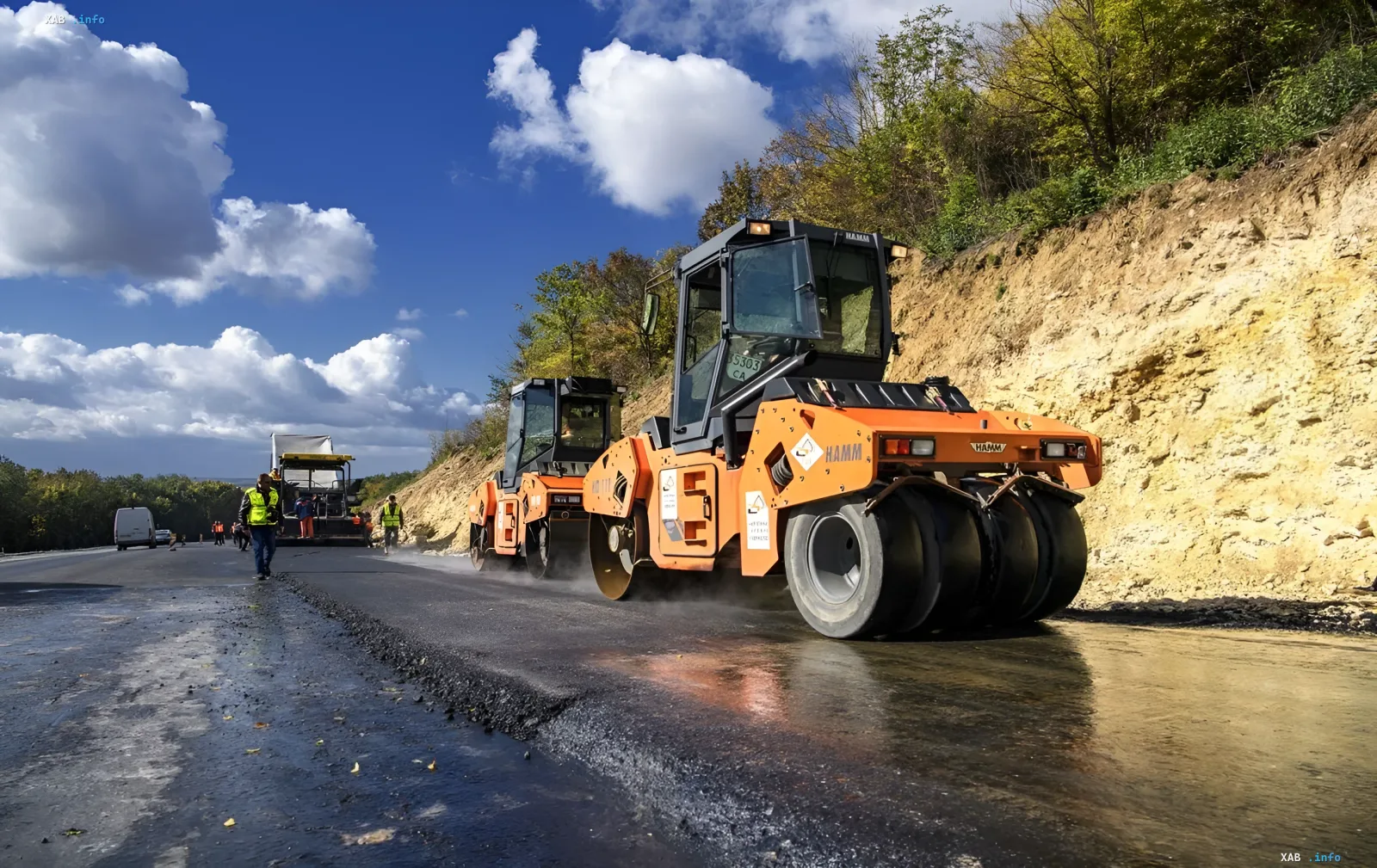 Road rollers and workers on an asphalt paving section of a highway, works halted by Avtostrada due to frozen state financing