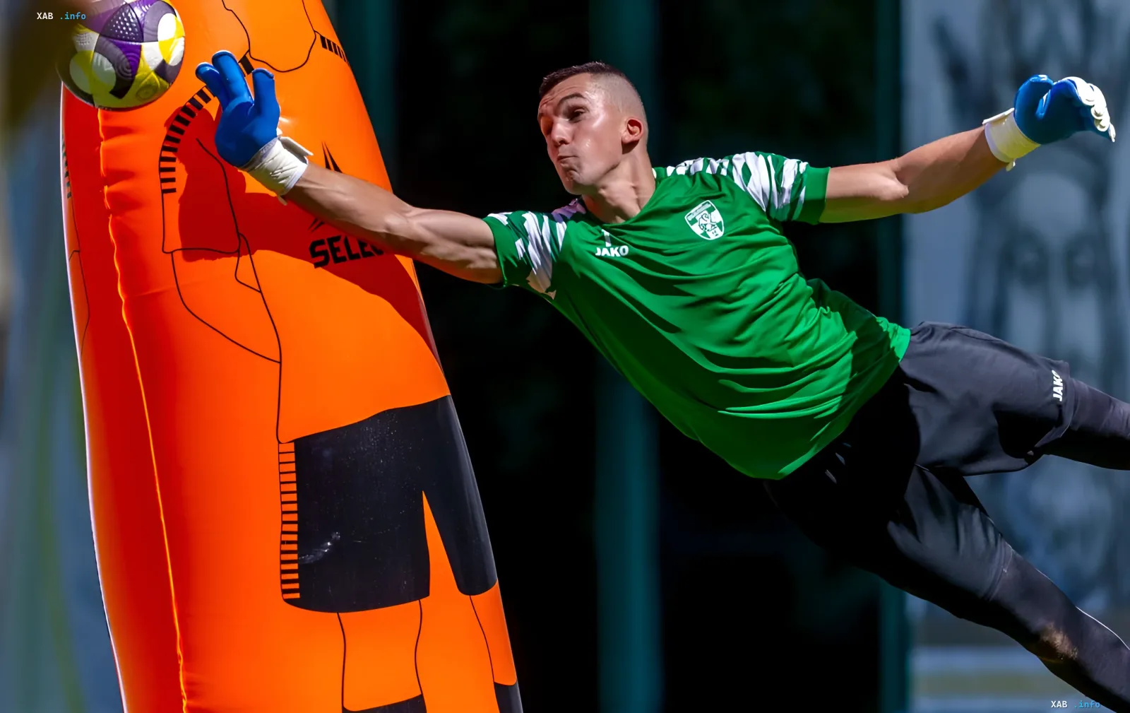 Tormann Fedorowski von Obolon in JAKO-Trikot bei einem Sprung während des Trainings mit einer Puppe