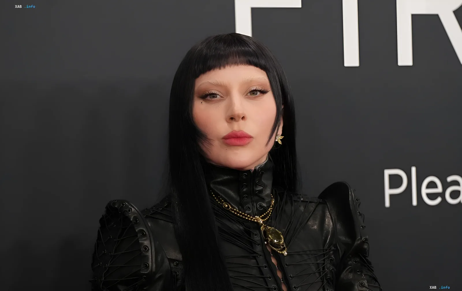 Lady Gaga in einem schwarzen Lederoutfit vor einem F1R-Logo-Hintergrund