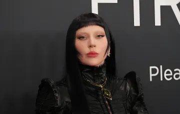 Lady Gaga in einem schwarzen Lederoutfit vor einem F1R-Logo-Hintergrund