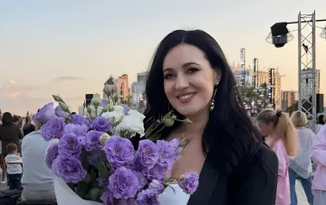 Соломия Витвицкая на 41-й неделе беременности с букетом фиолетовых и белых эустом на городской площади на закате