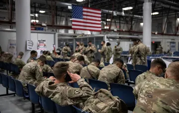 US soldiers in camouflage in a waiting hall with an American flag amid Pentagon talks of withdrawing troops from Europe