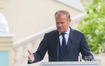 Donald Tusk at a podium warning that Russia is preparing strikes on NATO's eastern flank disguised as accidental incidents