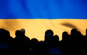 Силуэты людей на фоне украинского флага — возвращение граждан с оккупированных территорий