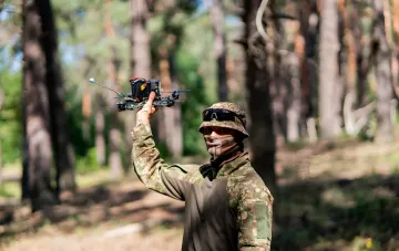 Operator of the 422nd LUFTWAFFE regiment holding a tactical drone in a forest during Operation Black Bird targeting the enemy power supply on the southern axis