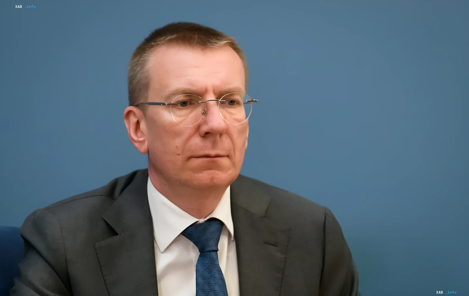 Президент Латвии на фоне синей стены в деловом костюме и очках, комментируя отставание Европы в перестройке ПВО под войну дронов