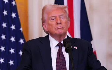 Дональд Трамп у микрофона на фоне американского флага перед запретом доступа CNN, Politico и MS NOW в Белый дом