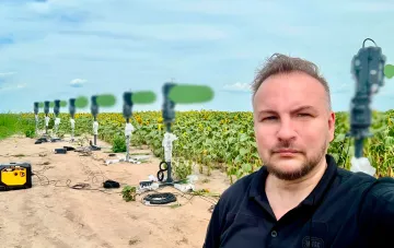 Дрон-перехоплювачі на тестовому полігоні в Україні: ряд вертикальних перехоплювачів на полі соняшників і інженер, що демонструє систему для знищення «Герань-5»
