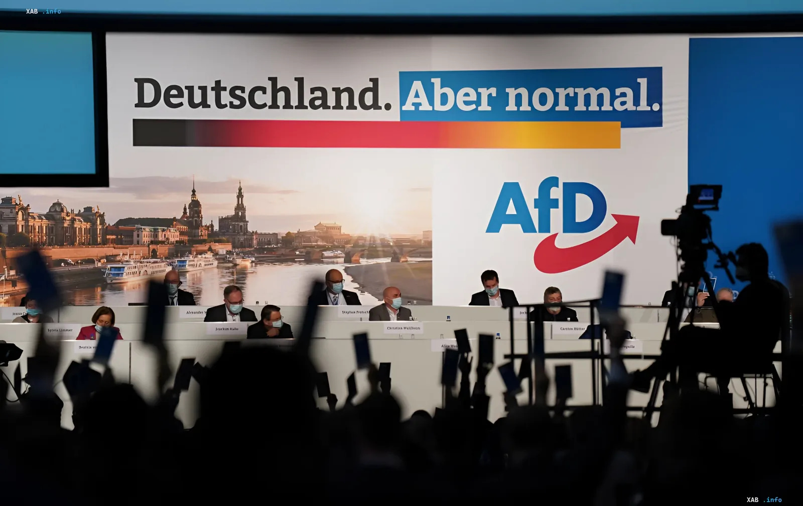 Съёмка экзитполов партии АдН (AfD) в Германии: журналисты с камерами перед сценой с логотипом партии и лозунгом «Deutschland. Aber normal.»