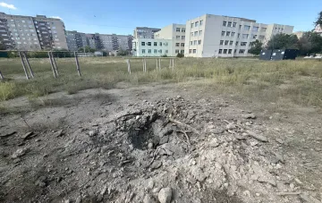 Яма від вибуху снаряда на порожньому полі в Краматорську після артилерійського обстрілу