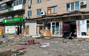 Пошкоджений фасад житлового будинку з зруйнованими вітринами магазинів після обстрілу в Дніпропетрівській області