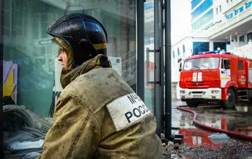 Russian EMERCOM firefighter in protective gear in front of a fire truck after drone attack on Bashneft refinery in Ufa