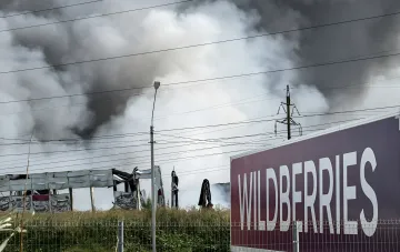 Зруйнований склад із стовпом диму на тлі вивіски Wildberries — наслідки ударів, через які селери подають сотні позовів