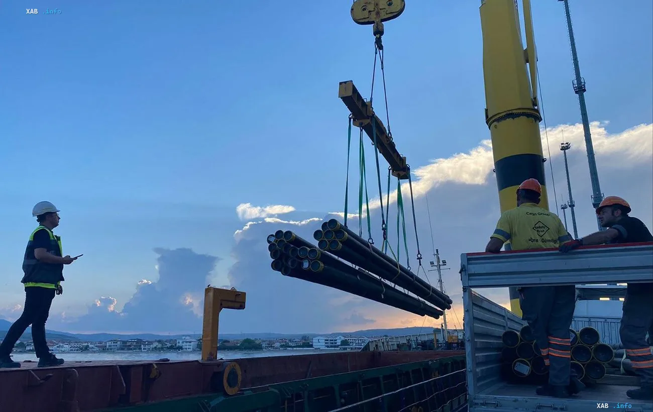 Робітники та кран із пучком труб на зупиненій після балістичного удару площадці «Інтерпайп» у Дніпрі