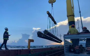 Робітники та кран із пучком труб на зупиненій після балістичного удару площадці «Інтерпайп» у Дніпрі
