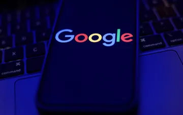 Логотип Google на экране смартфона в синем неоновом свете — символ тайной работы аналитика против хакерской империи TeamPCP