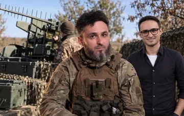 Ihor Lastotschkin in Tarnanzug mit Bart vor einer elektronischen Kampfführung-Station und Tarnnetzen an der Front der 93. Brigade