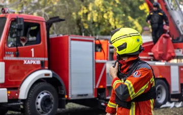 Пожарный харьковской службы спасения в защитном шлеме у пожарного автомобиля с надписью «Харків» после атаки российских дронов