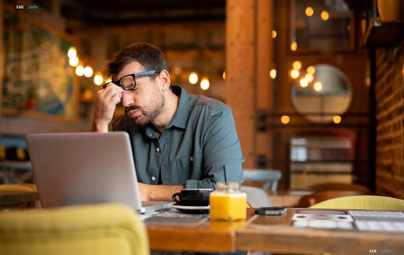 A tired sole proprietor works on a laptop in a cafe amid news of a new 85,000 euro turnover threshold for VAT