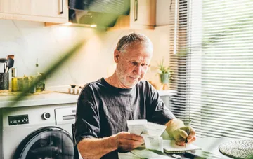 Senior man reviewing paper certificates at home after ordering them online from Ukraine's Pension Fund