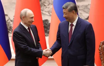 Владимир Путин и Си Цзиньпин пожимают руки на фоне флагов России и Китая перед саммитом АТЭС