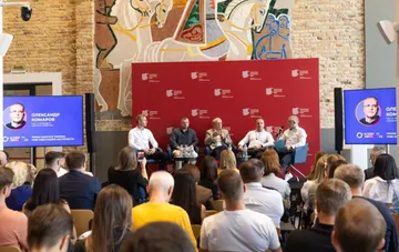 Panel discussion on the Ukrainian capital market at the KIEF TALKS conference: speakers on stage in front of an audience, with the KIEF logo and speaker Oleksandr Komarov on the screens