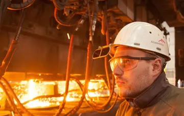 Steel plant worker in an ArcelorMittal hard hat in front of molten steel amid the Ukrainian metallurgy crisis