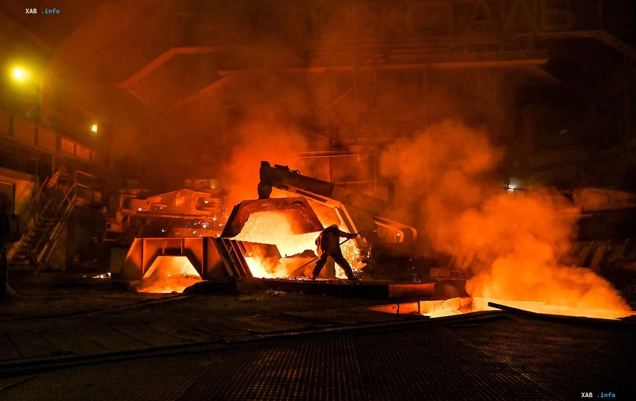 Pouring of liquid steel at a Ukrainian steel mill at night: orange glow, smoke and a worker by the furnace amid the industry crisis