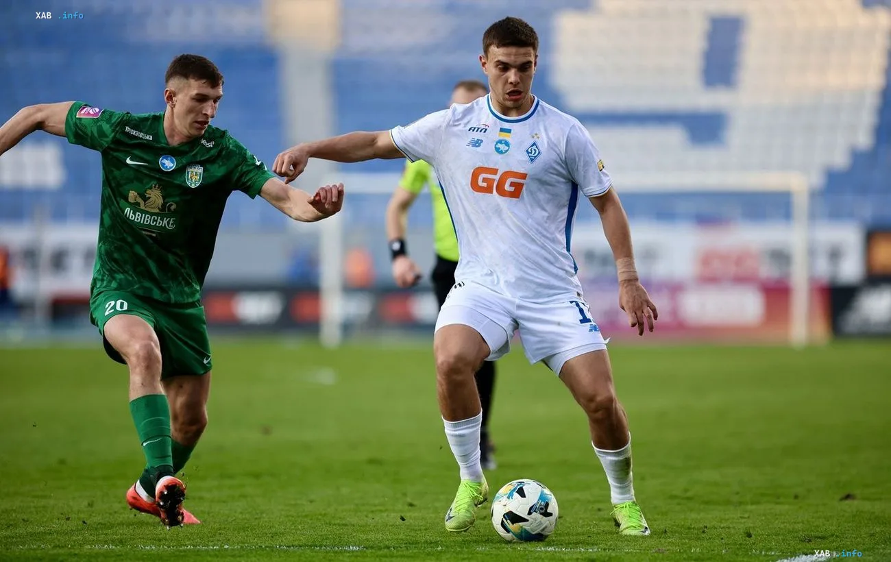 UPL match: a Dynamo player in a white kit with the GG logo controls the ball under pressure from a Veres player in a green kit during the Ukrainian championship