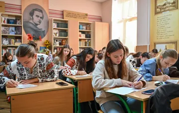 Female students writing at their desks during a lesson in a Ukrainian school classroom, illustrating the news about flexible class schedules of up to 35 minutes approved by Ukraine's Ministry of Education