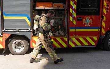 Firefighter in protective gear with breathing apparatus walking away from a fire truck after the shelling of Velykyi Burluk in Kharkiv region