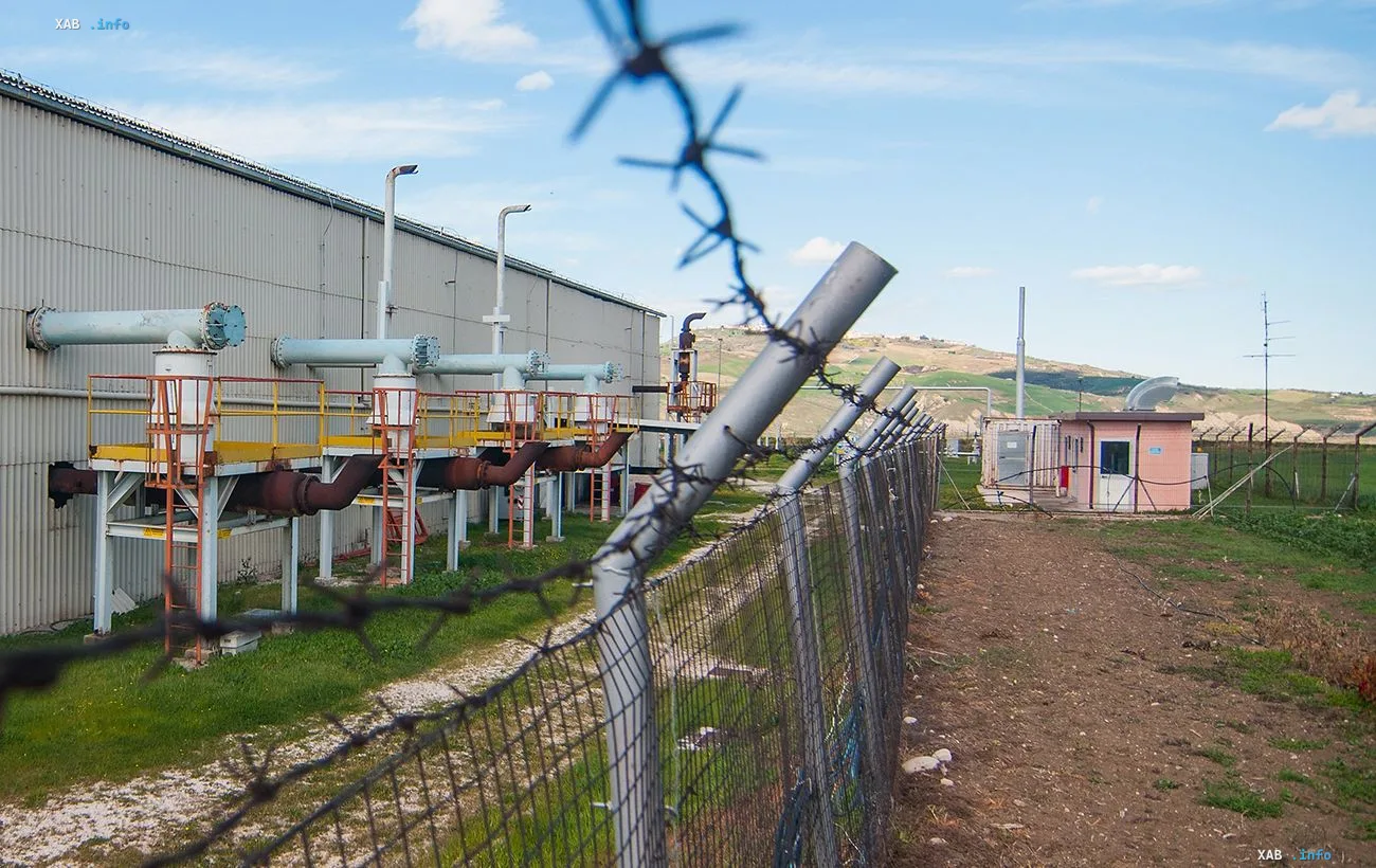 Газопромышленный объект на Жуковской площади в Полтавской области: трубы, платформы и ограда с колючей проволокой на фоне холмистого ландшафта