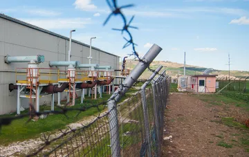 Газопромышленный объект на Жуковской площади в Полтавской области: трубы, платформы и ограда с колючей проволокой на фоне холмистого ландшафта