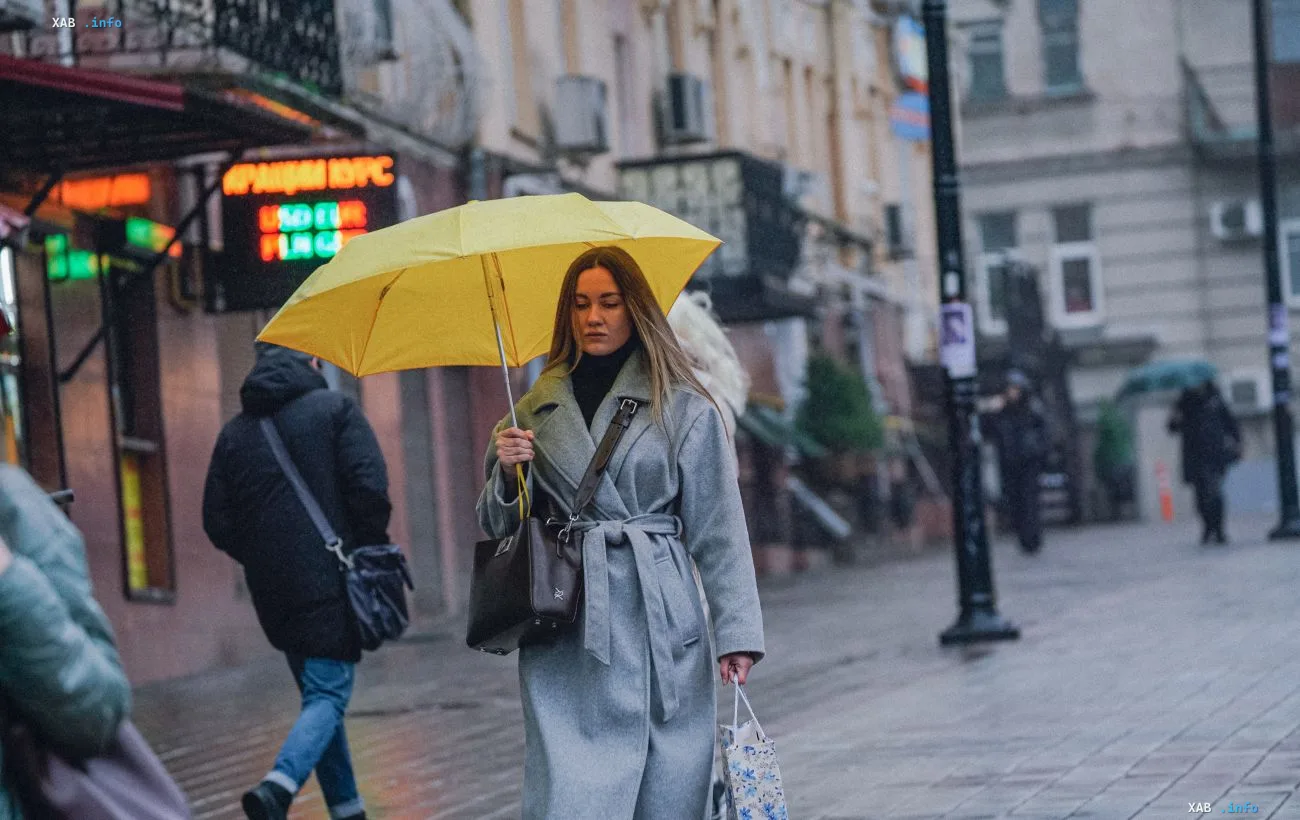 Woman with a yellow umbrella walking on a wet city street in the rain during the Black Sea cyclone