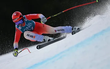 A skier carving a sharp turn on a snow-covered course in international FIS cross-country and alpine skiing competitions